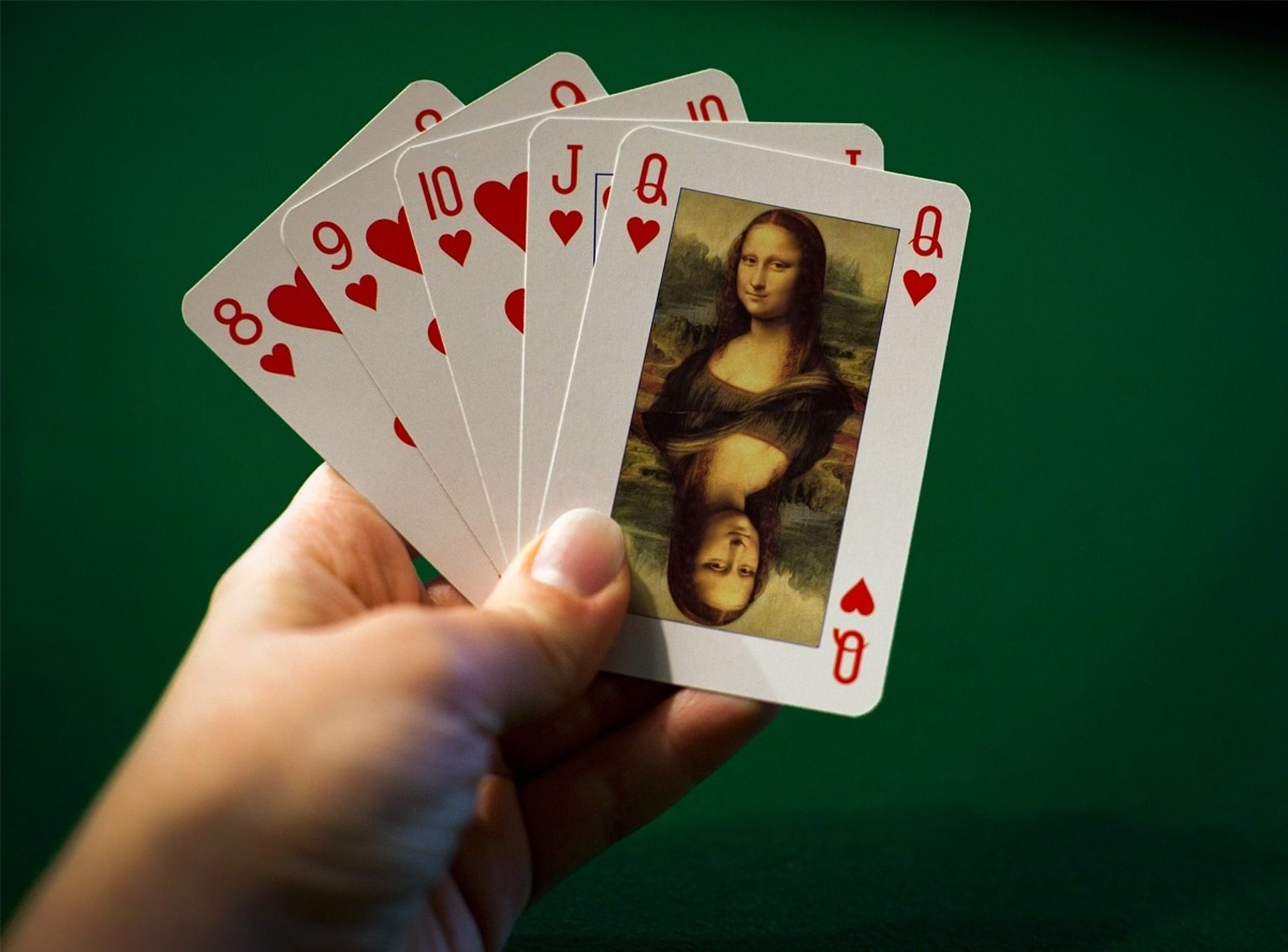 Jemand hält Spielkarte in der Hand, auf denen Mona Lisa abgebildet ist